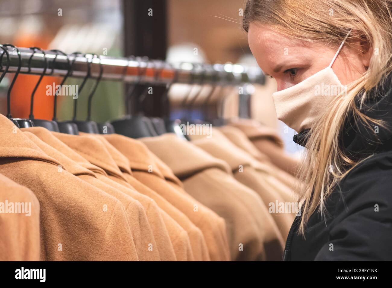 Blond girl in a shop with mask and plastic gloves, shopping during covid or coronavirus lockdown Stock Photo