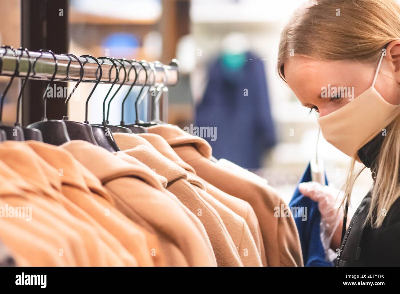 Blond girl in a shop with mask and plastic gloves, shopping during covid or coronavirus lockdown Stock Photo