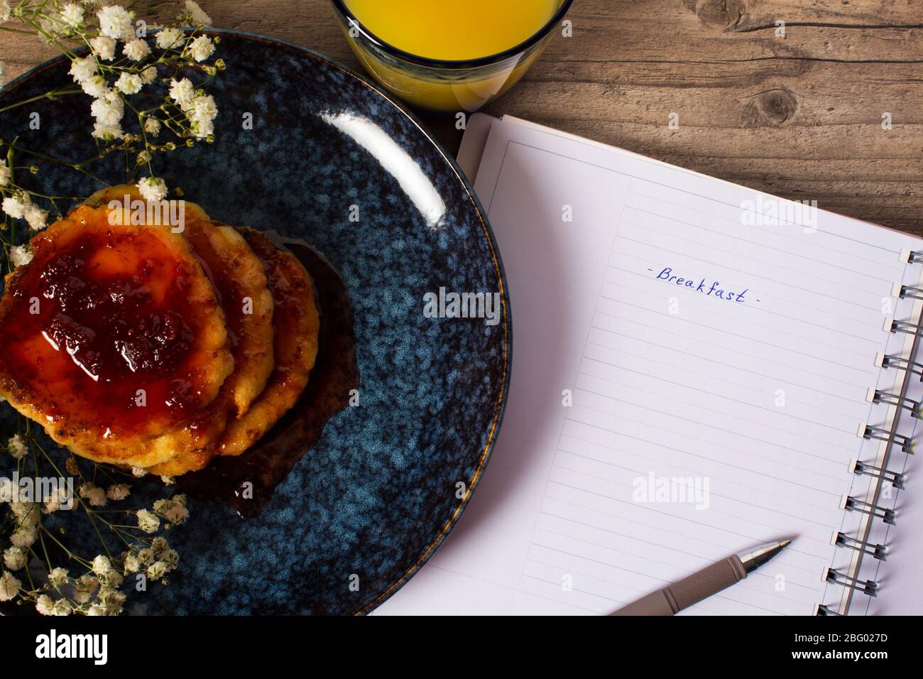 Beautiful Breakfast. Pancakes with jam and orange juice. Flowers and stylish dishes. Daily planner with the inscription Breakfast. A healthy life styl Stock Photo