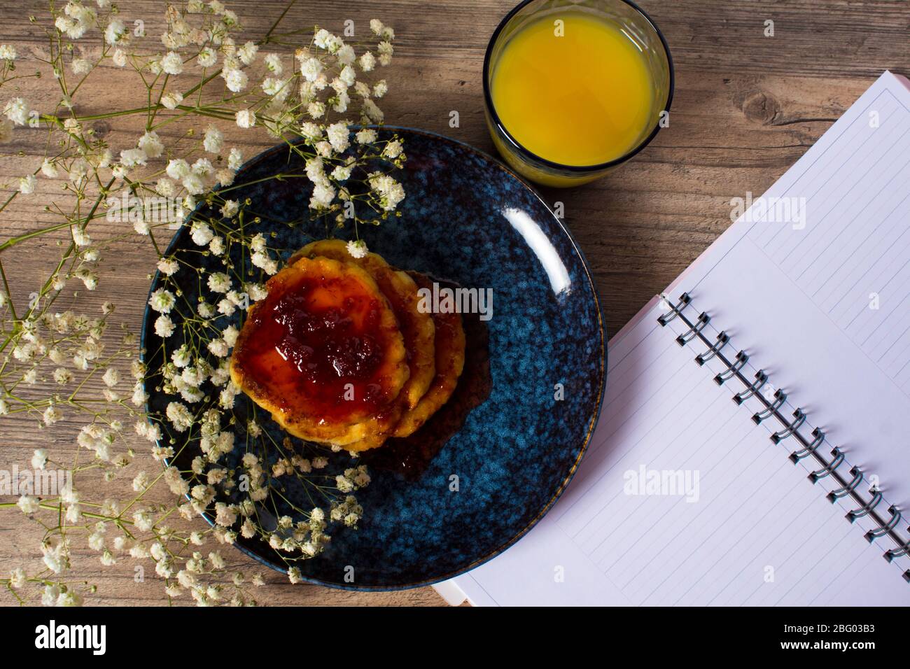 Beautiful Breakfast. Pancakes with jam and orange juice. Flowers and stylish dishes. A diary with blank pages. A healthy life style. Flat lay. Luxury Stock Photo