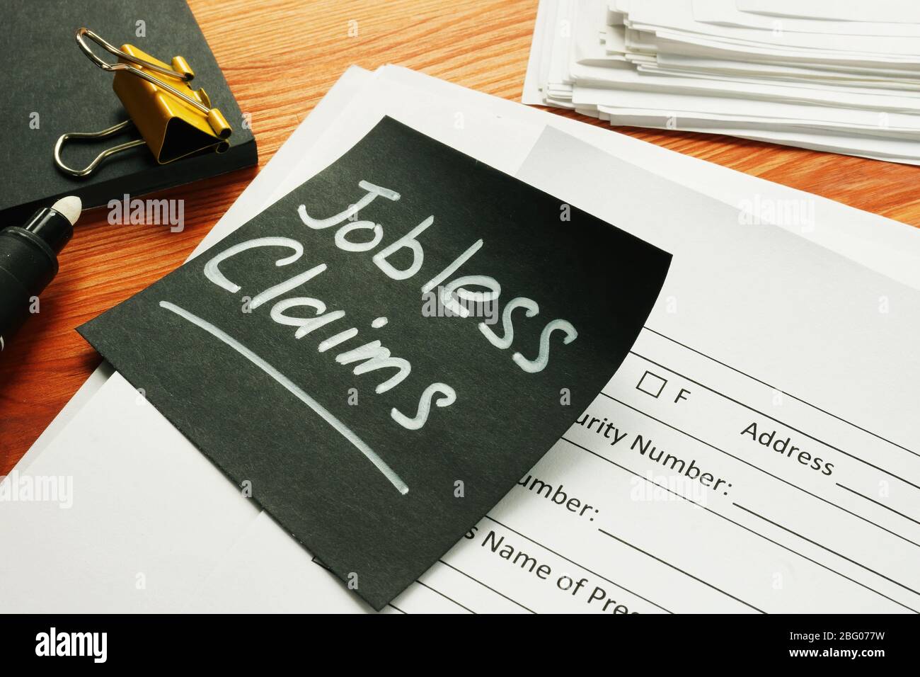 Jobless claims memo stick and pile of documents. Stock Photo