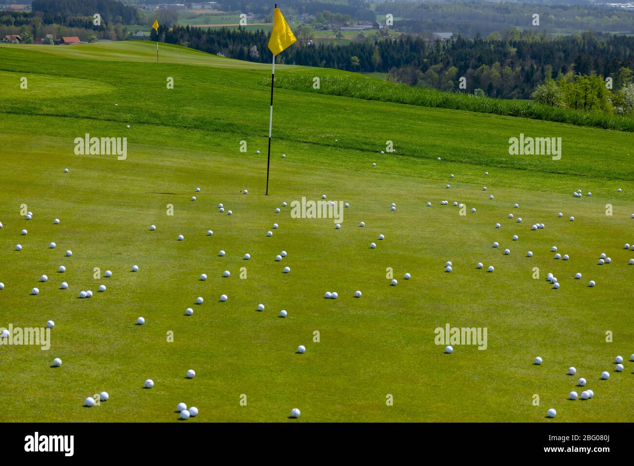 Golf Green with Flag Stick and Many Golf Balls in Switzerland. Stock Photo