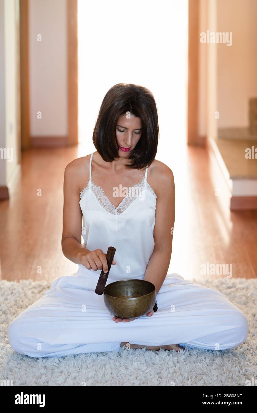 Woman doing yoga with tibetian singing bowl at home Stock Photo