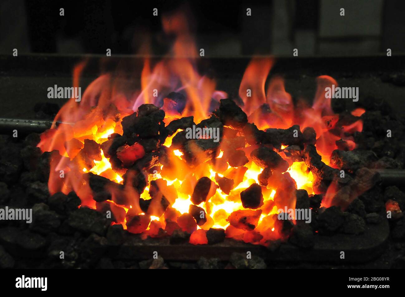 Glowing coal in a forge while forging Stock Photo