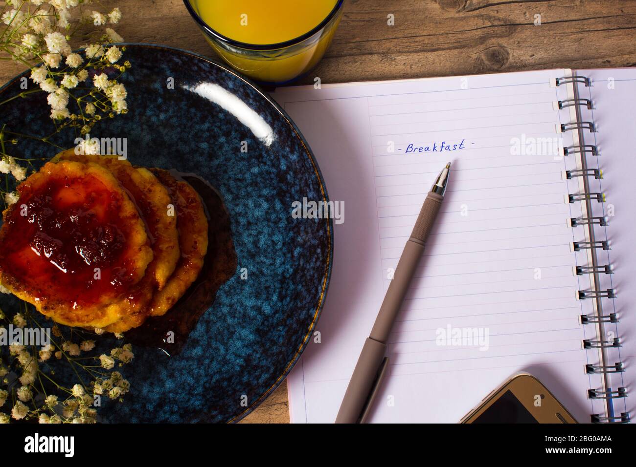 Beautiful Breakfast. Pancakes with jam and orange juice. Flowers and stylish dishes. Daily planner with the inscription Breakfast. A healthy life styl Stock Photo