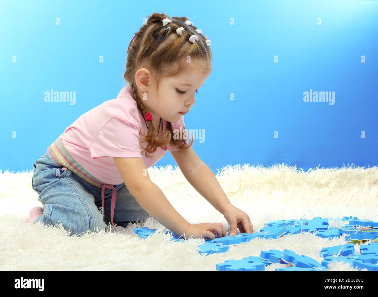 cute little girl playing with puzzles, on blue background Stock Photo ...
