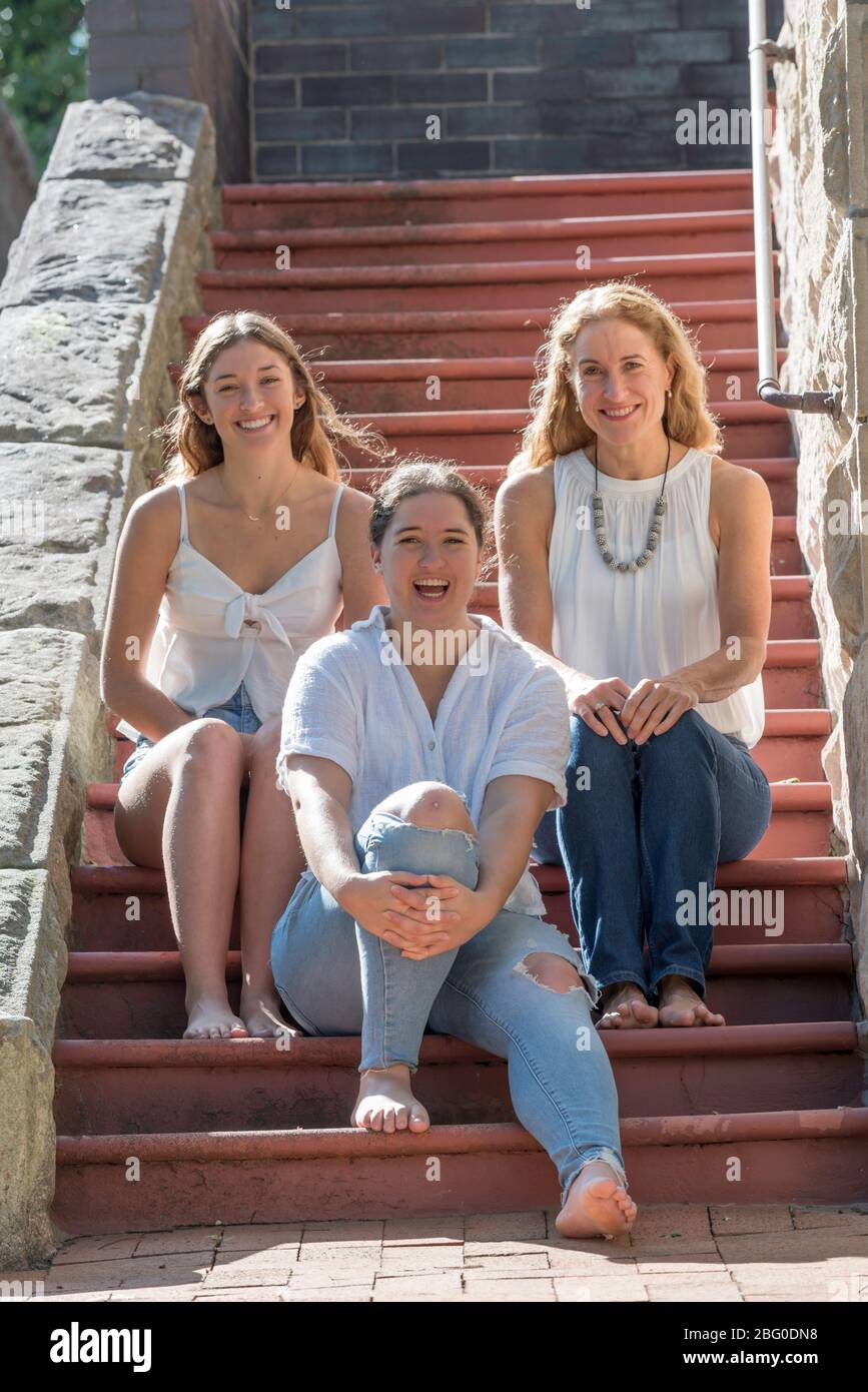 A smiling Australian family of mother and two adult daughters sit, bathed  in morning Autumn sunlight, at the front steps of their Sydney home Stock  Photo - Alamy