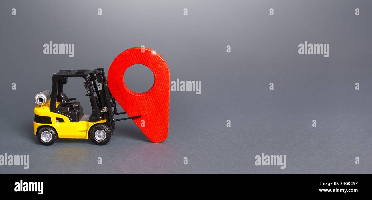 The forklift sets a red pin location indicator. Delivery and distribution of goods products. Logistics, transportation. Trade, cargo freight traffic. Stock Photo