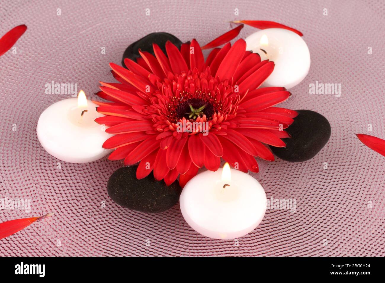 spa stones with flower and candles in water on plate Stock Photo - Alamy