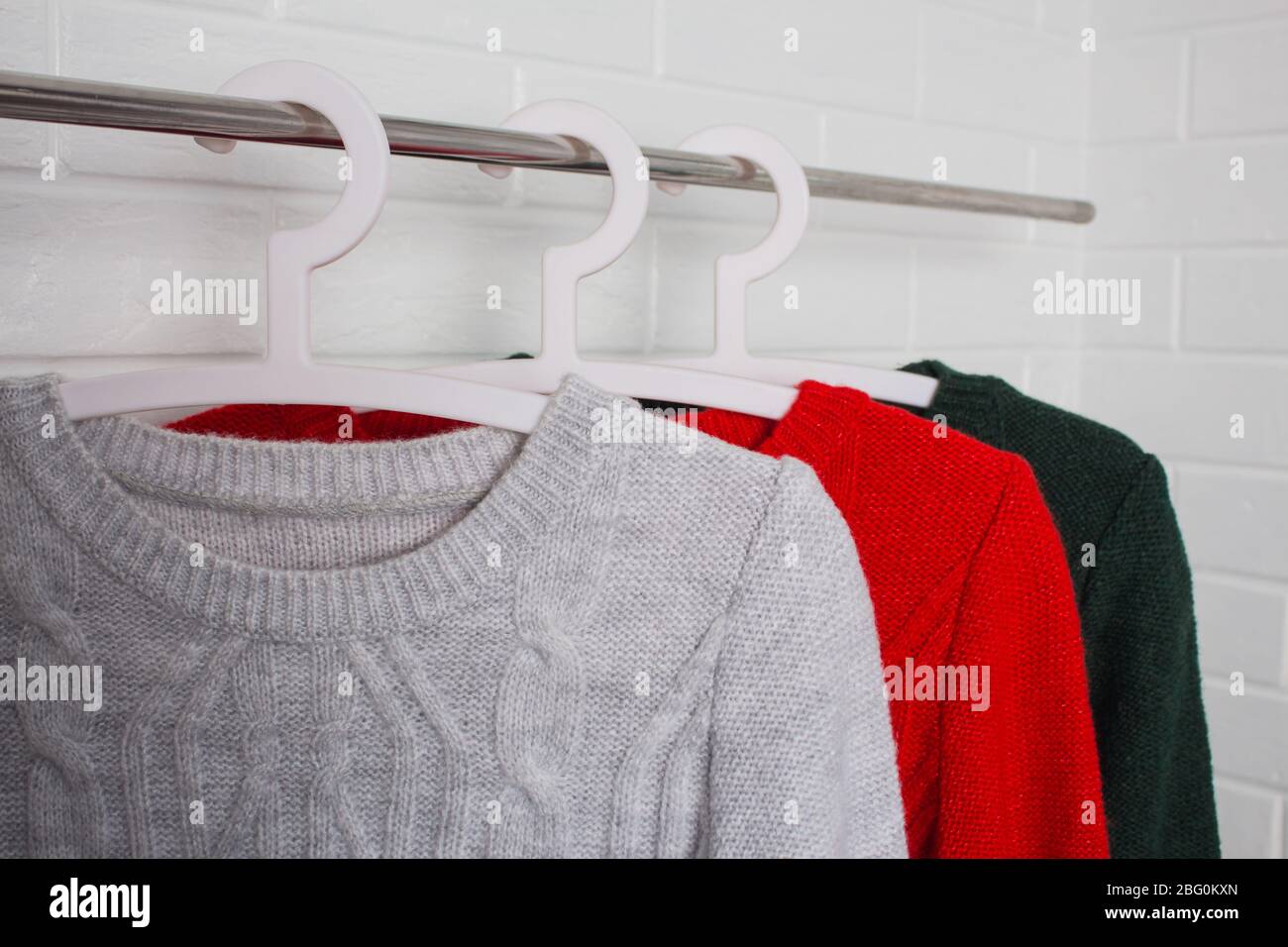 Clothes hang on hangers. Sweaters in red, green and melange colors