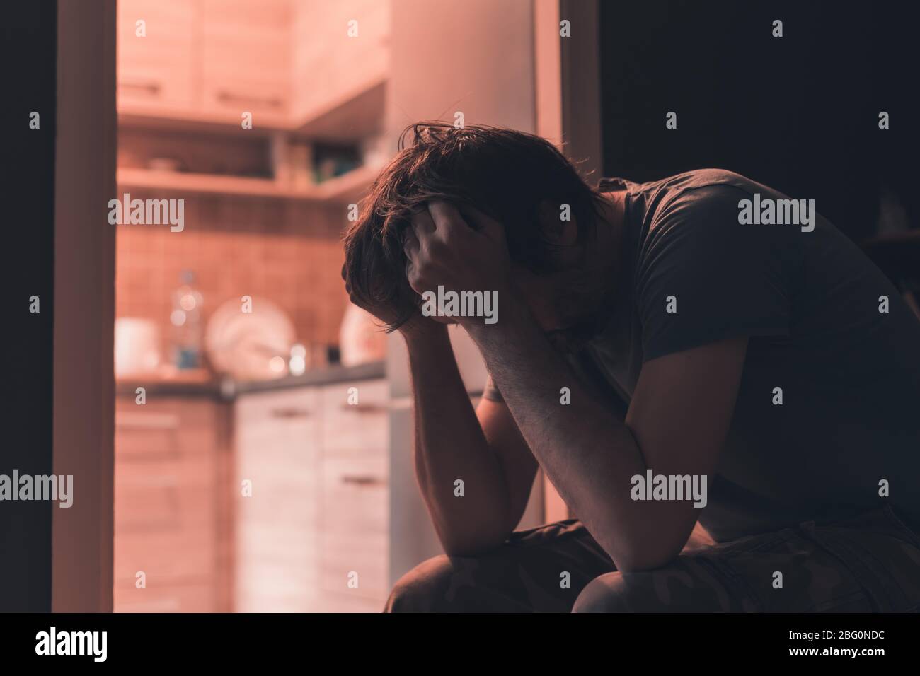Depressed sad man crying in dark room with head in hands, selective focus Stock Photo