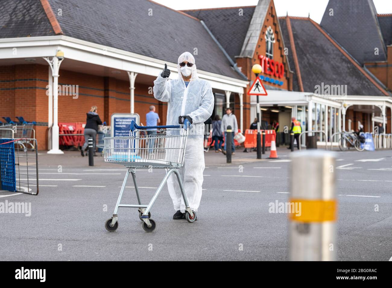 Shopper wears a full hazmat suit and mask at the Cheltenham Tesco Superstore during the Coronavirus pandemic. Stock Photo