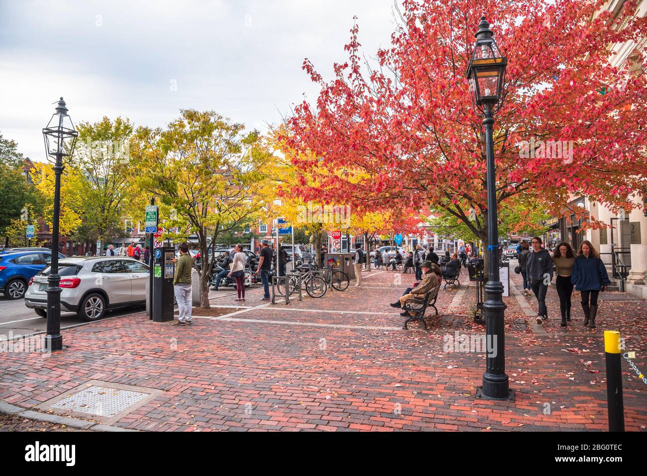 People enjoying a warm autumn afternoon in a small brick square along Pleasant Street in downtown Portsmouth Stock Photo