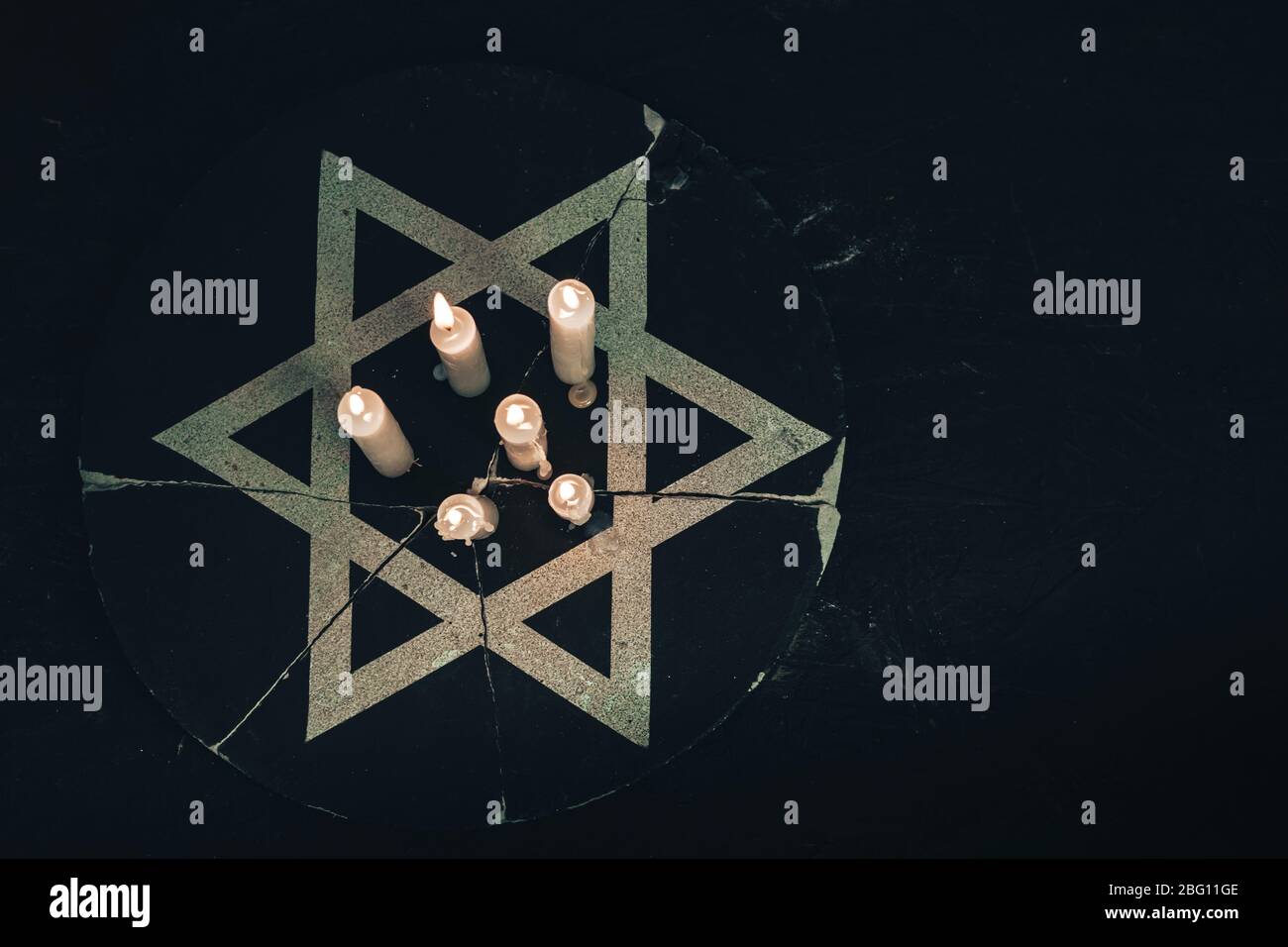 Six burning candles and the Star of David against on a black background. Stock Photo
