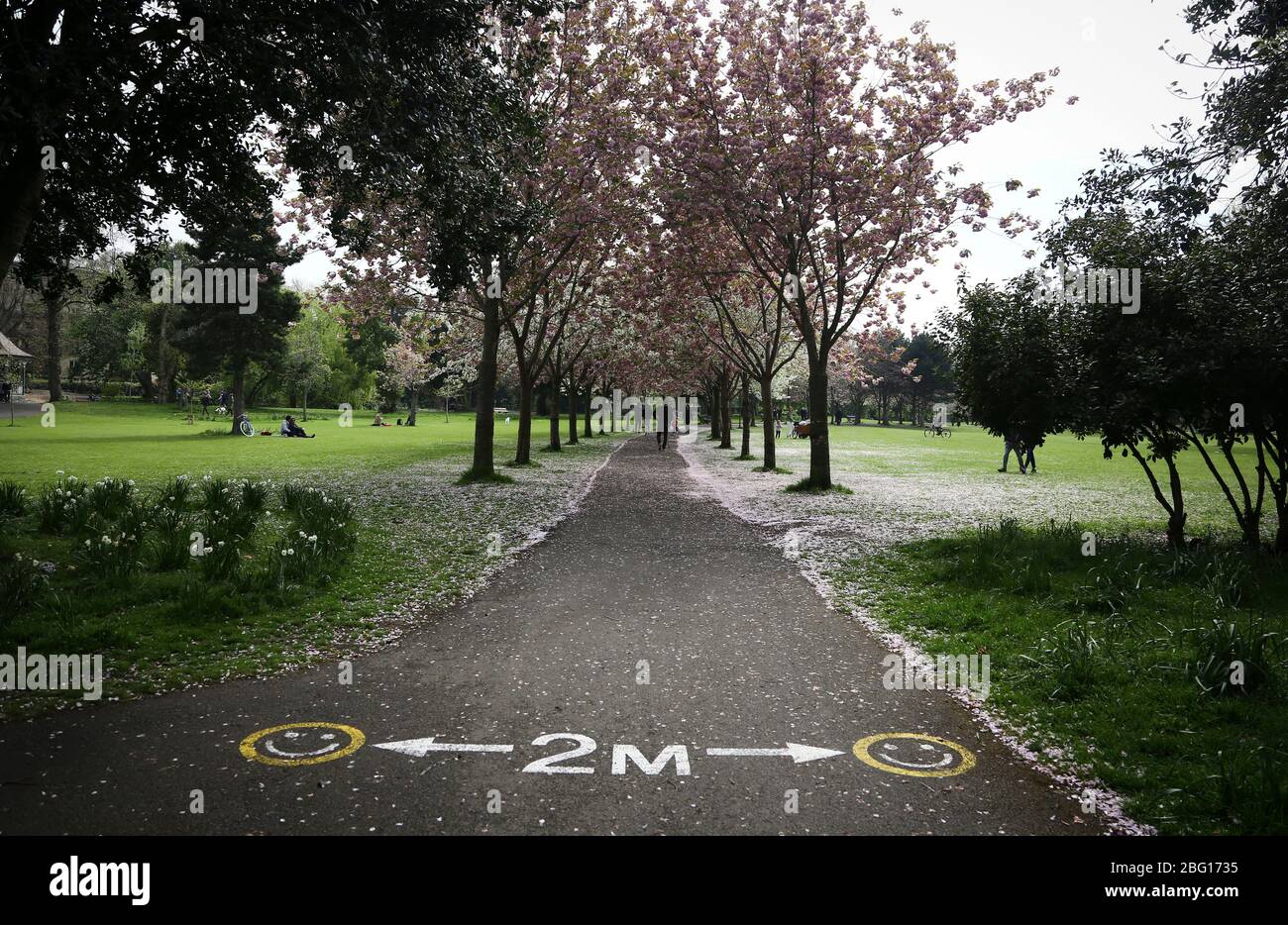 Dublin, Ireland - April 19, 2020: a two metres social distancing message written on the pavement at the entrance to Herbert Park. Stock Photo