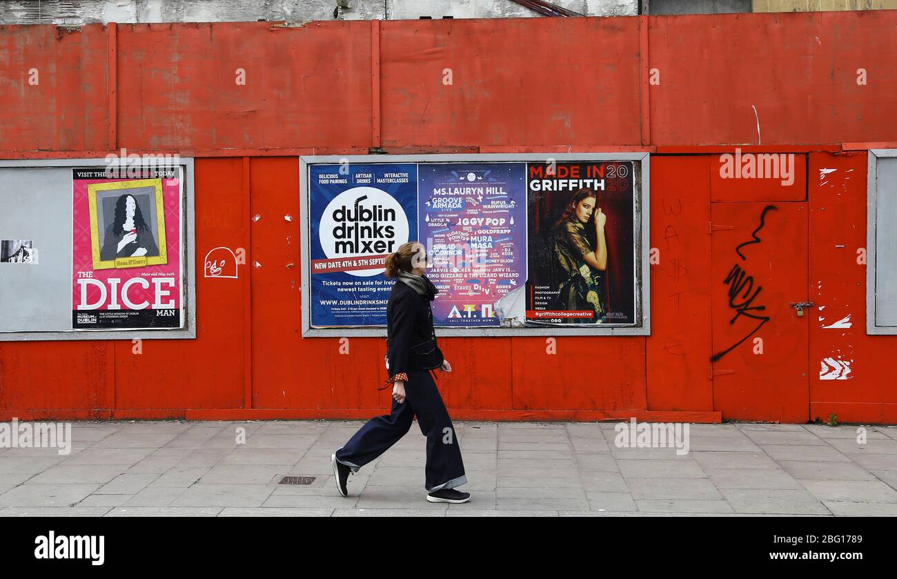 Dublin, Ireland - April 19, 2020: a woman passing posters for concerts and events now cancelled due to Covid-19 lockdown restrictions. Stock Photo