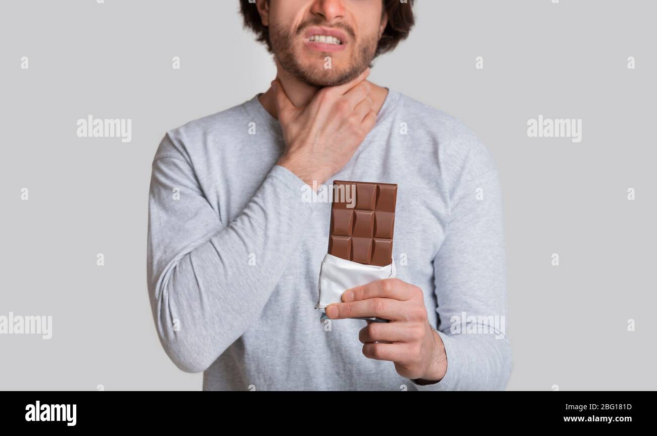 Allergic to chocolate. Man feels bad, holding his throat Stock Photo