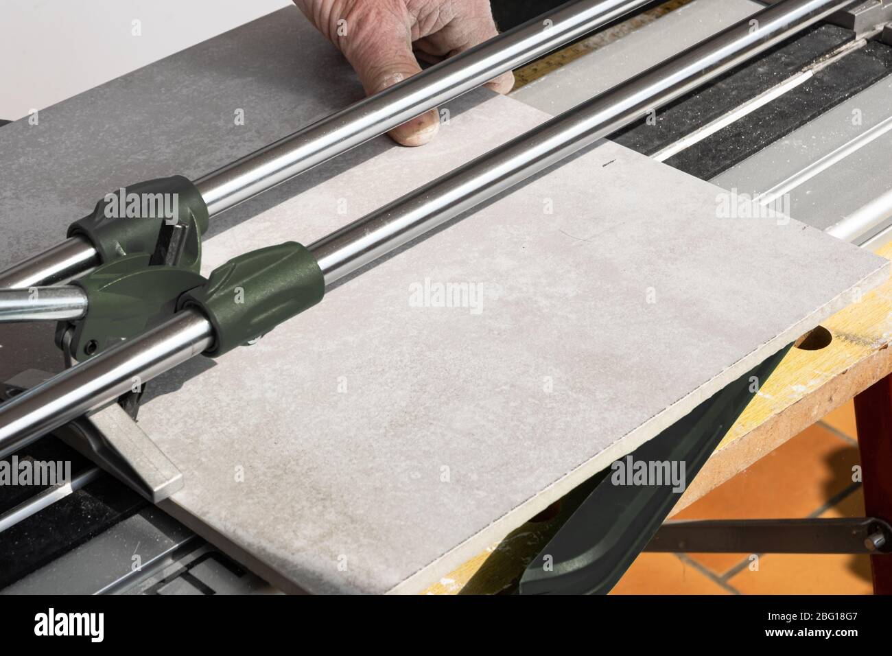 the mason cuts a ceramic tile with a tile cutter Stock Photo
