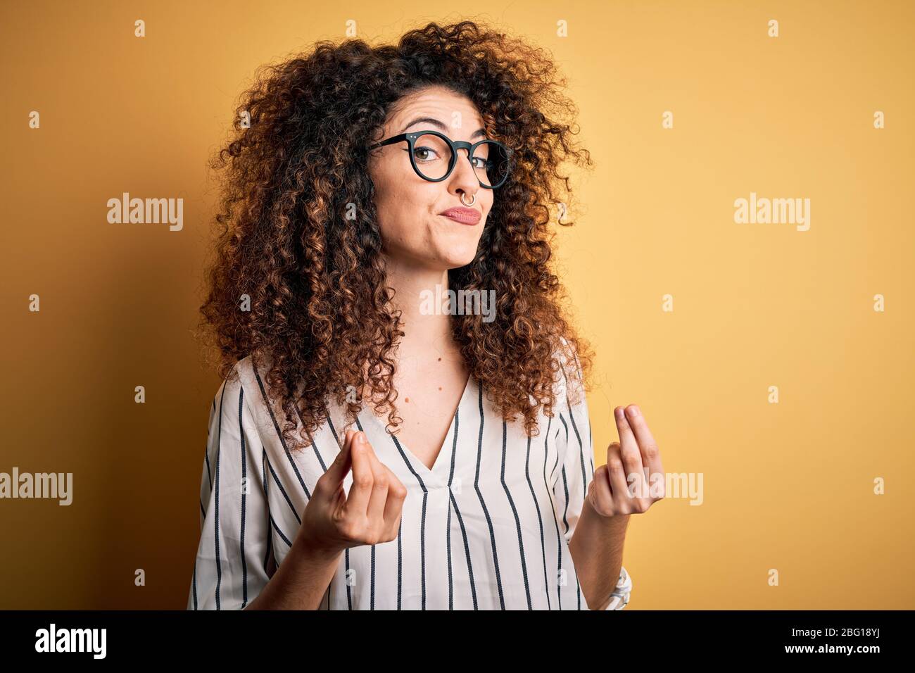 Young beautiful woman with curly hair and piercing wearing striped
