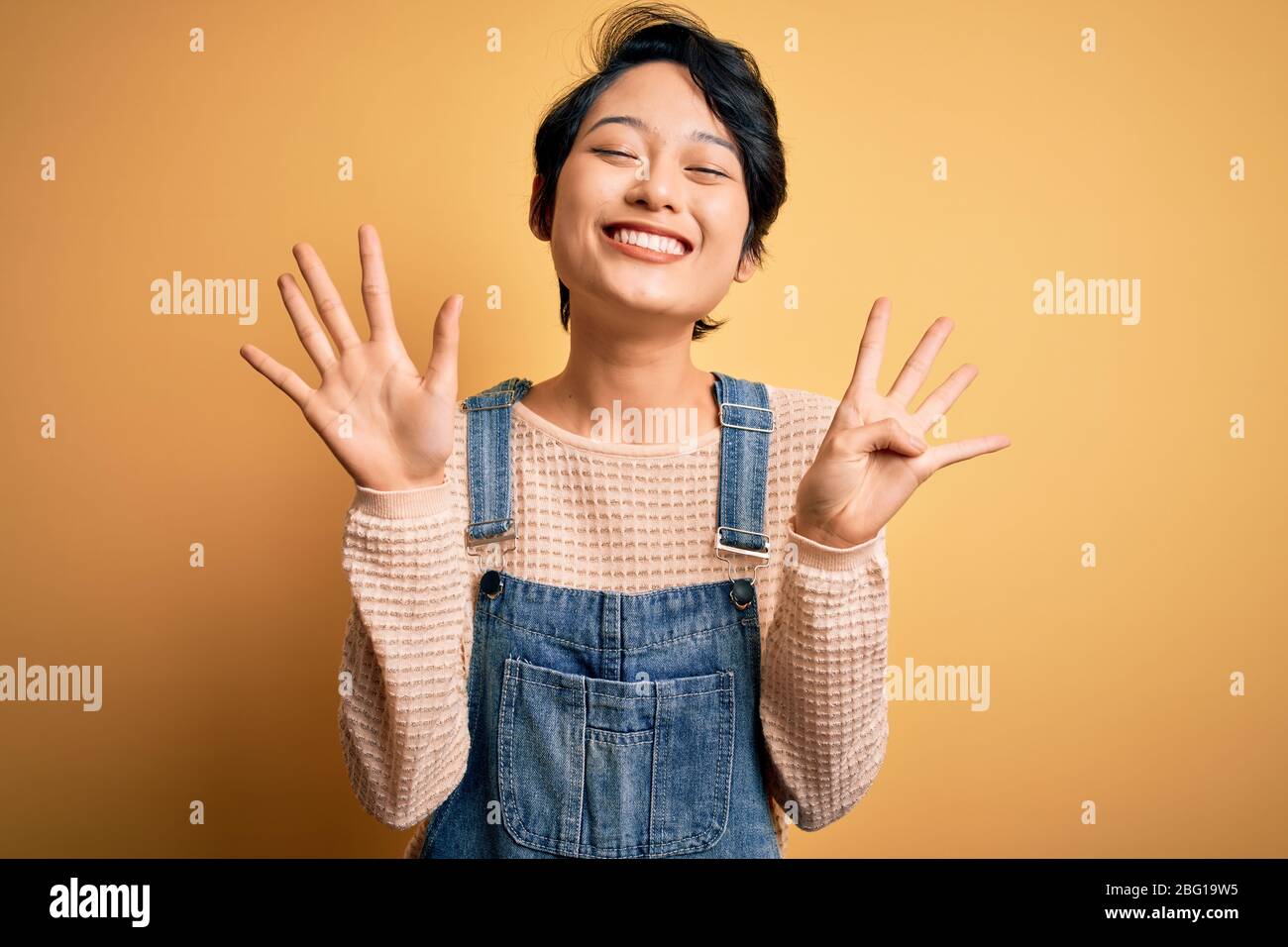 Young beautiful asian girl wearing casual denim overalls over isolated ...