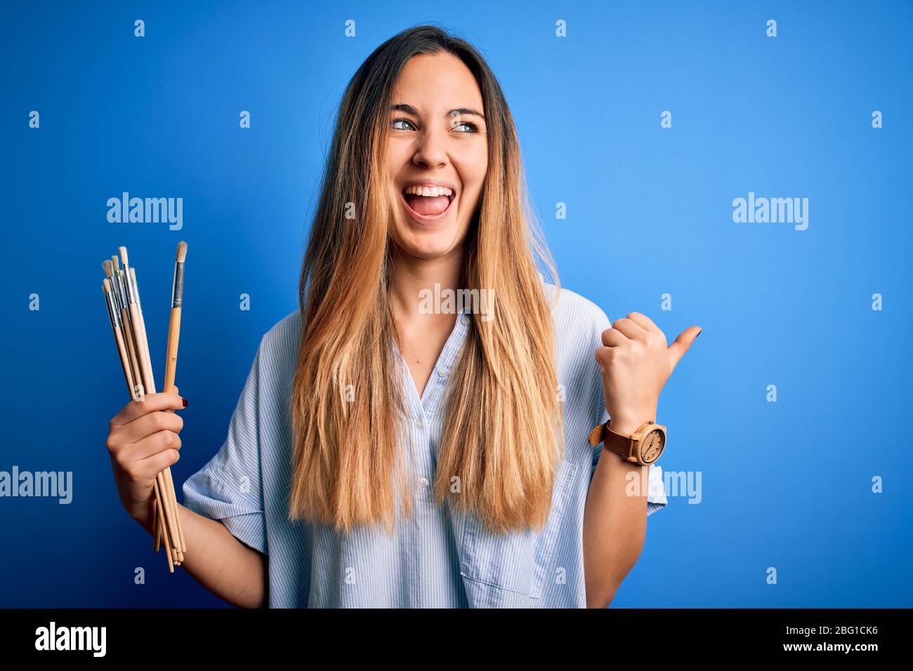 Young beautiful blonde artist woman with blue eyes painting using paint ...