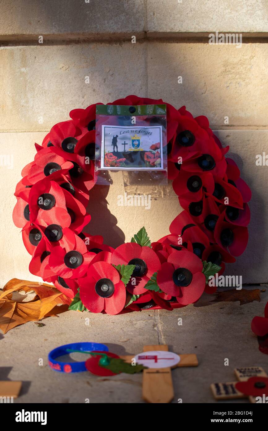 A red poppy wreath laid in front of a war memorial on remembrance day Stock Photo