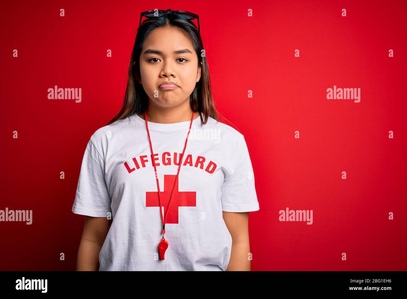 Young asian lifeguard girl wearing t-shirt with red cross using whistle ...