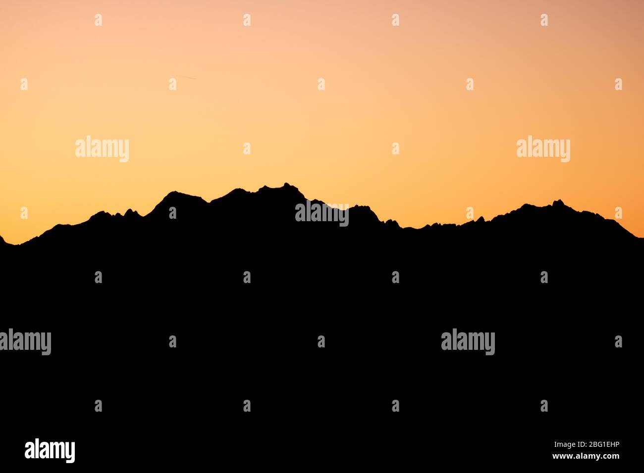 Orange Sun Setting Behind the Mountains Stock Photo