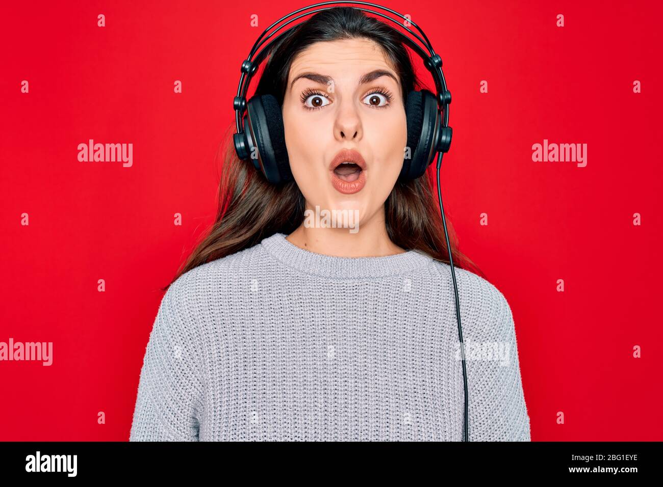 Young beautiful girl wearing modern headphones listening to music over ...