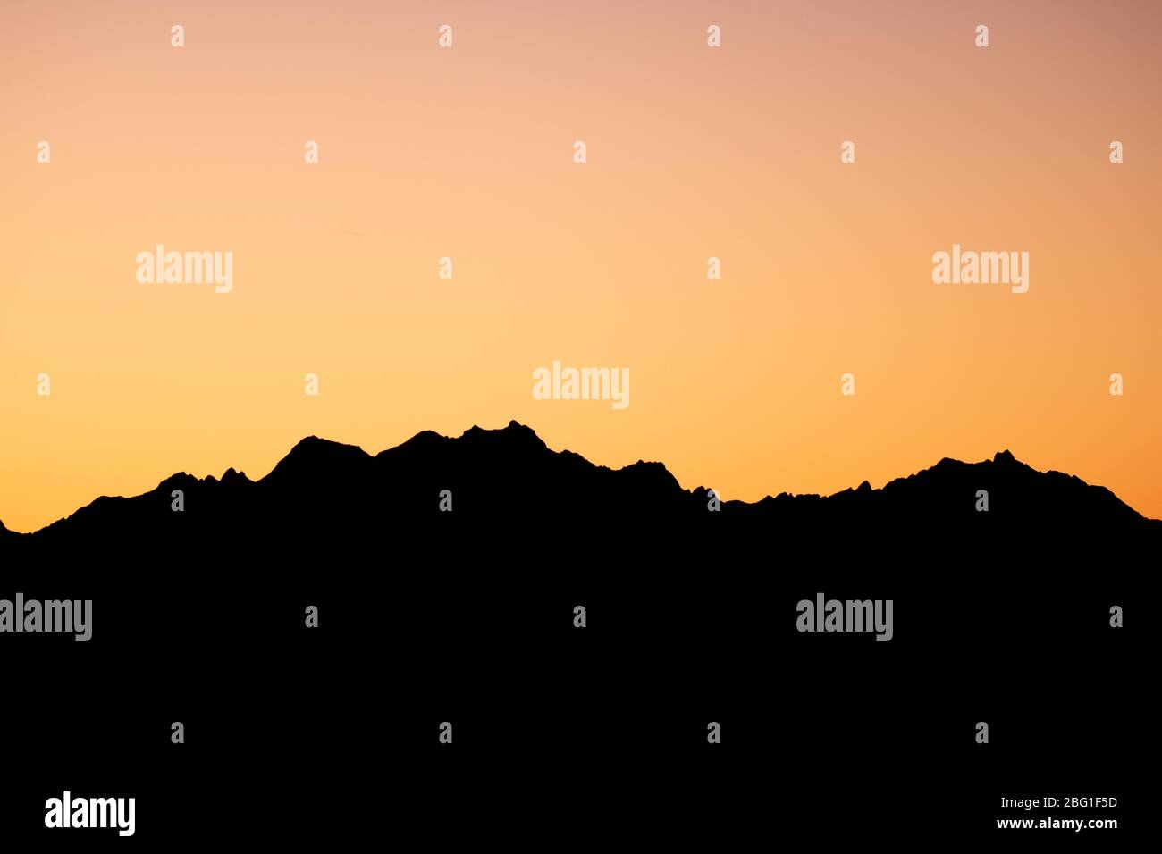 Orange Sun Setting Behind the Mountains Stock Photo