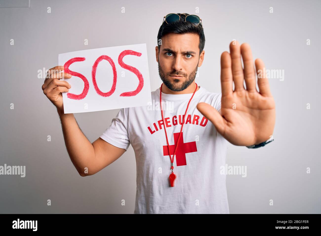 Young lifeguard man with beard wearing whistle holding paper with sos ...