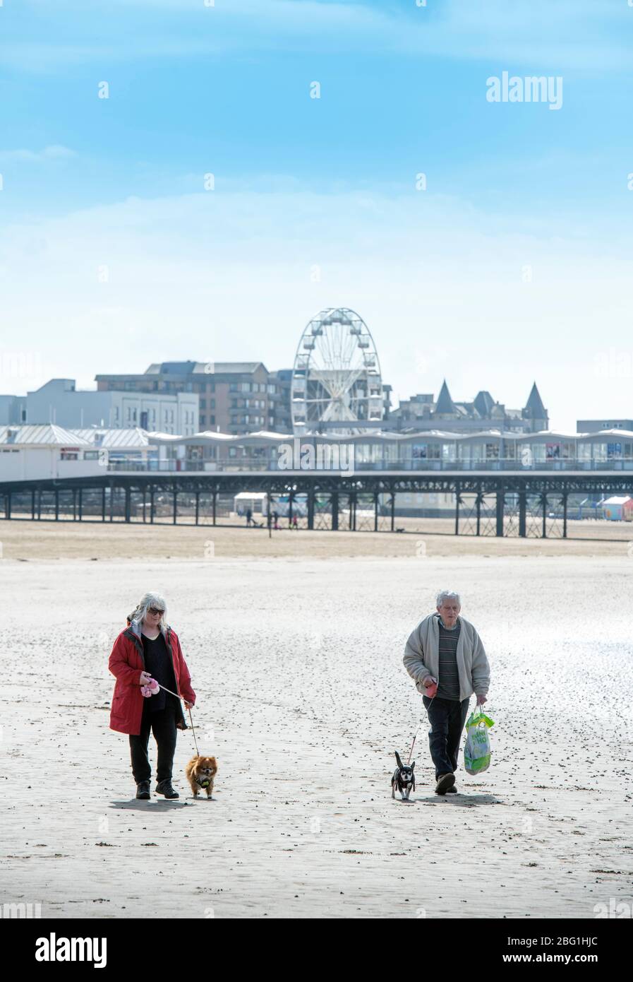 A retired couple cross the near deserted beach at Weston-super-Mare during the Coronavirus lockdown, UK Stock Photo