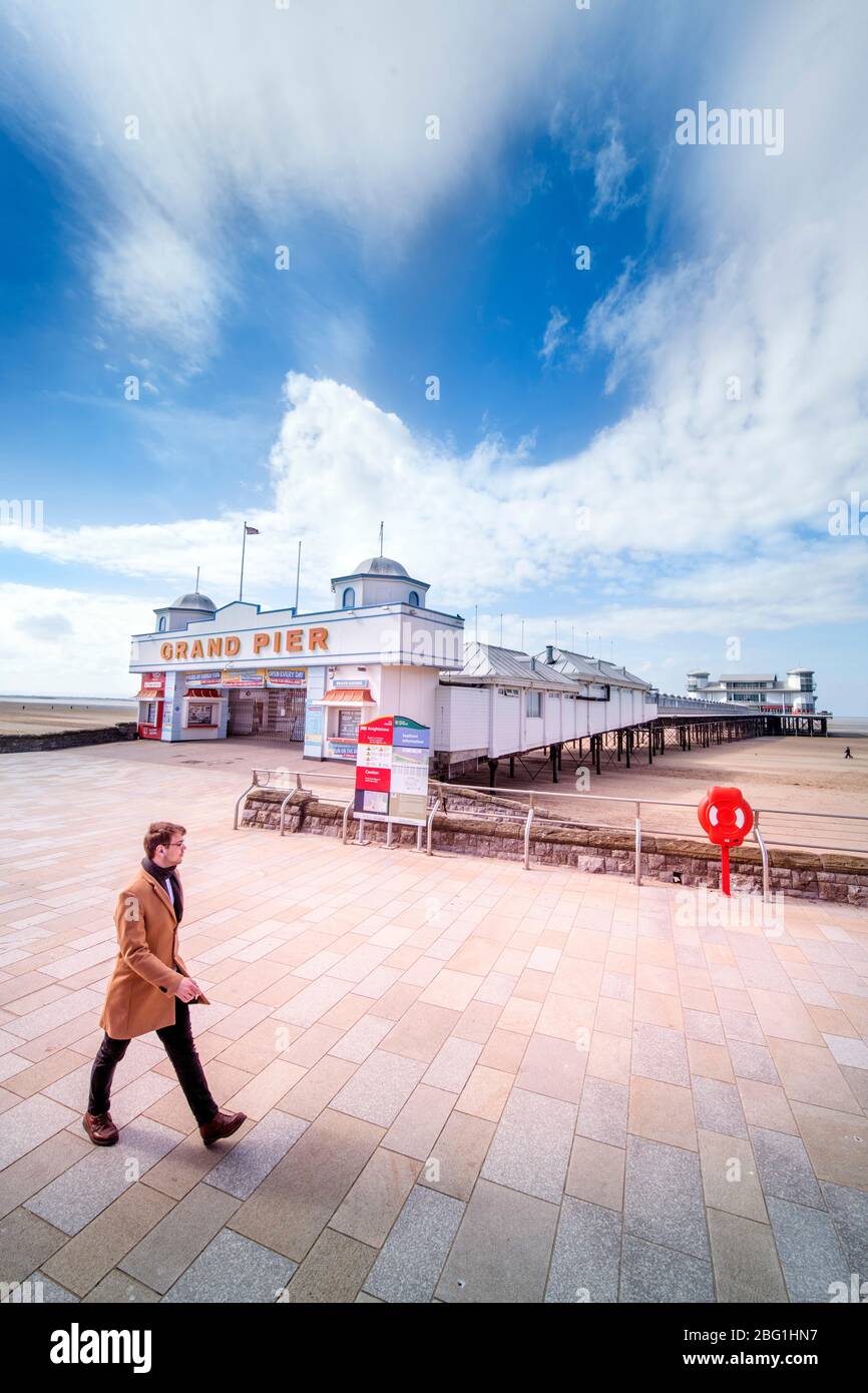 A man taking his daily permitted exercise passes the Grand Pier at Weston-super-Mare during the Coronavirus lockdown, UK Stock Photo