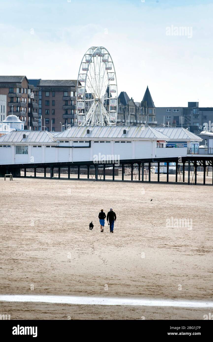 A couple take their daily permitted exercise on the near deserted beach at Weston-super-Mare during the Coronavirus lockdown, UK Stock Photo