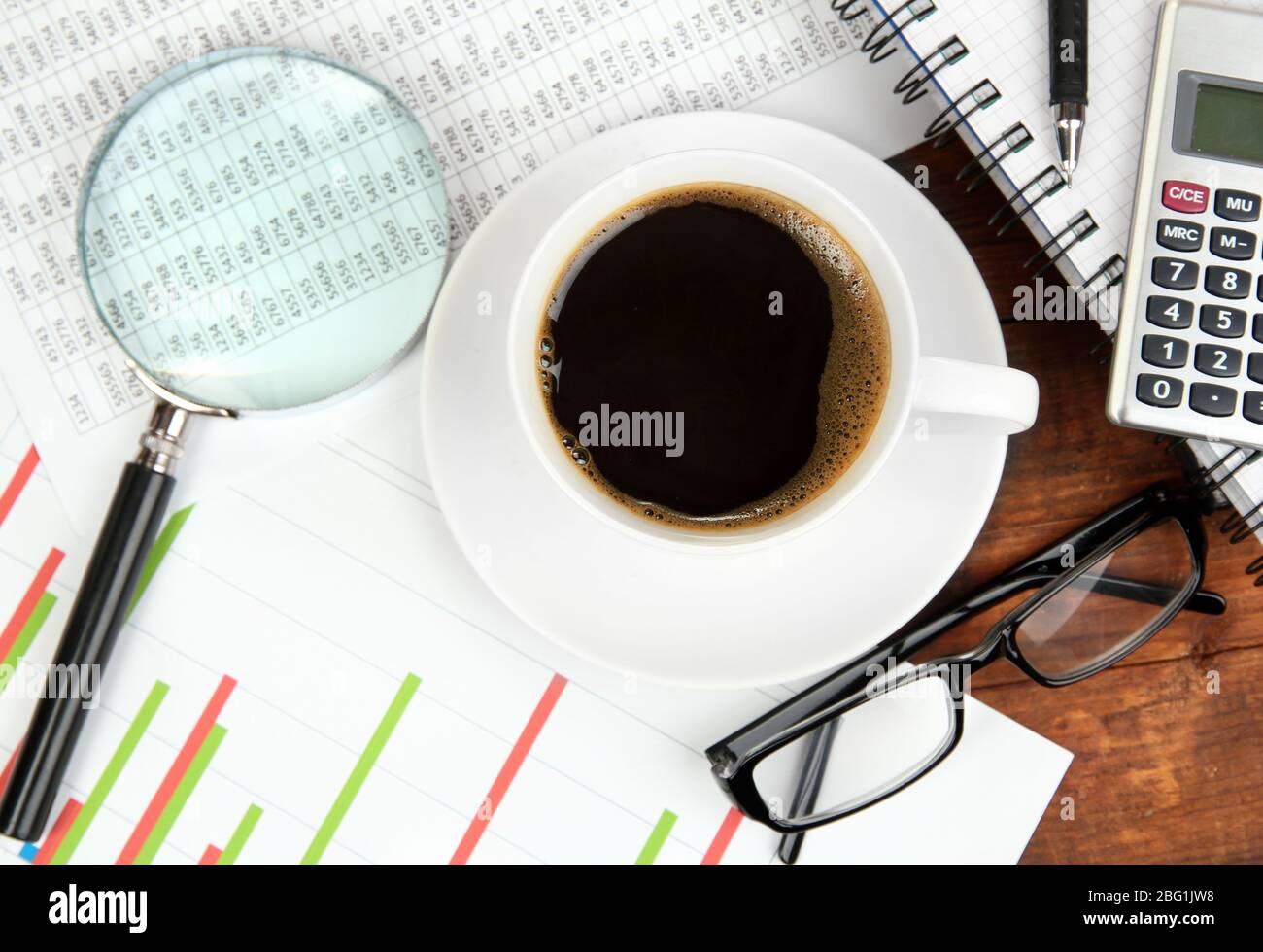 Cup of coffee on worktable covered with documents close up Stock Photo