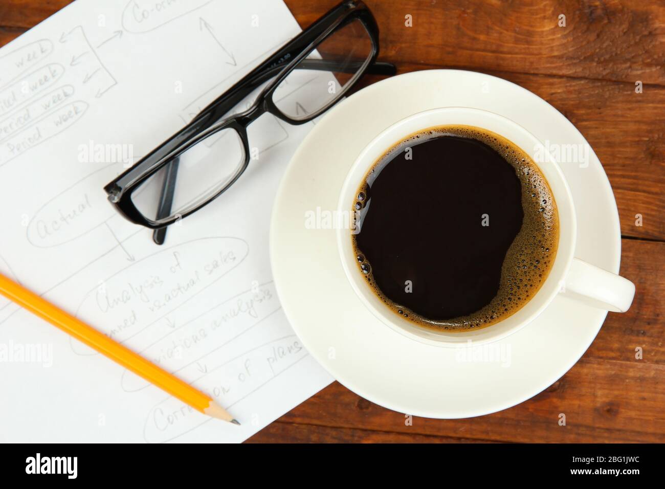 Cup of coffee on worktable covered with documents close up Stock Photo