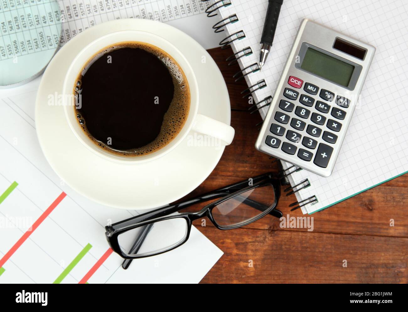 Cup of coffee on worktable covered with documents close up Stock Photo