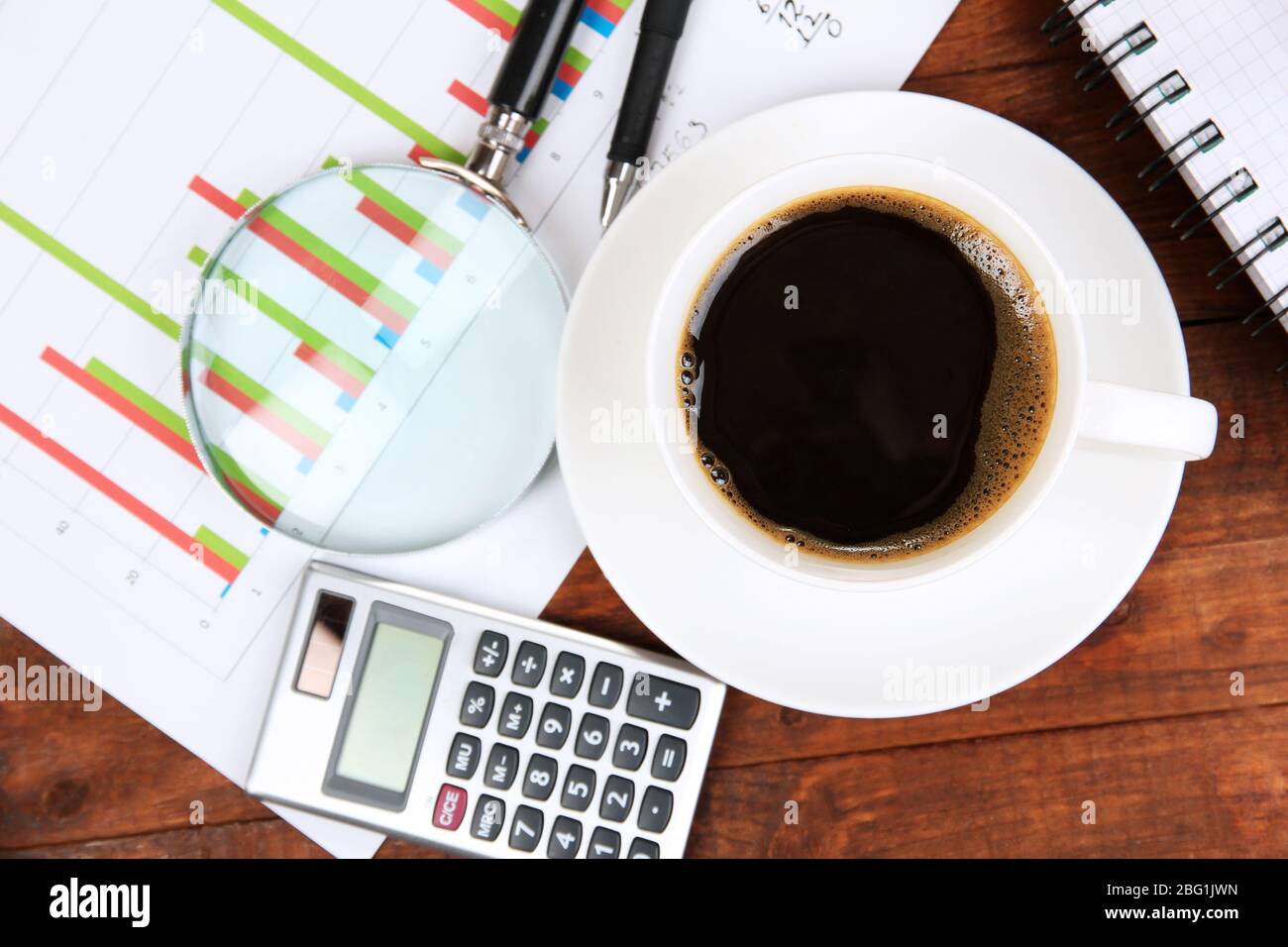 Cup of coffee on worktable covered with documents close up Stock Photo