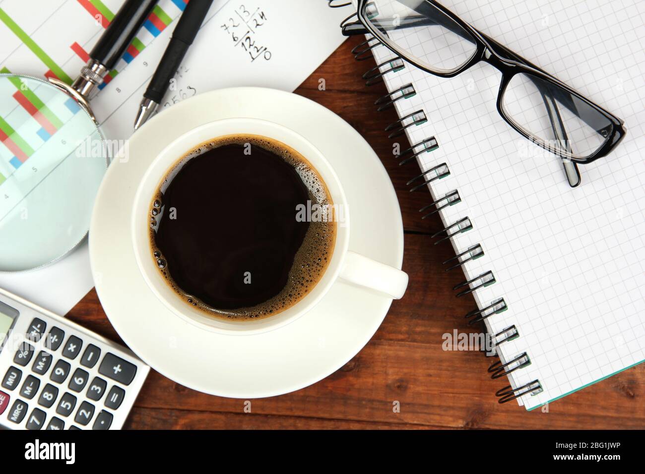 Cup of coffee on worktable covered with documents close up Stock Photo