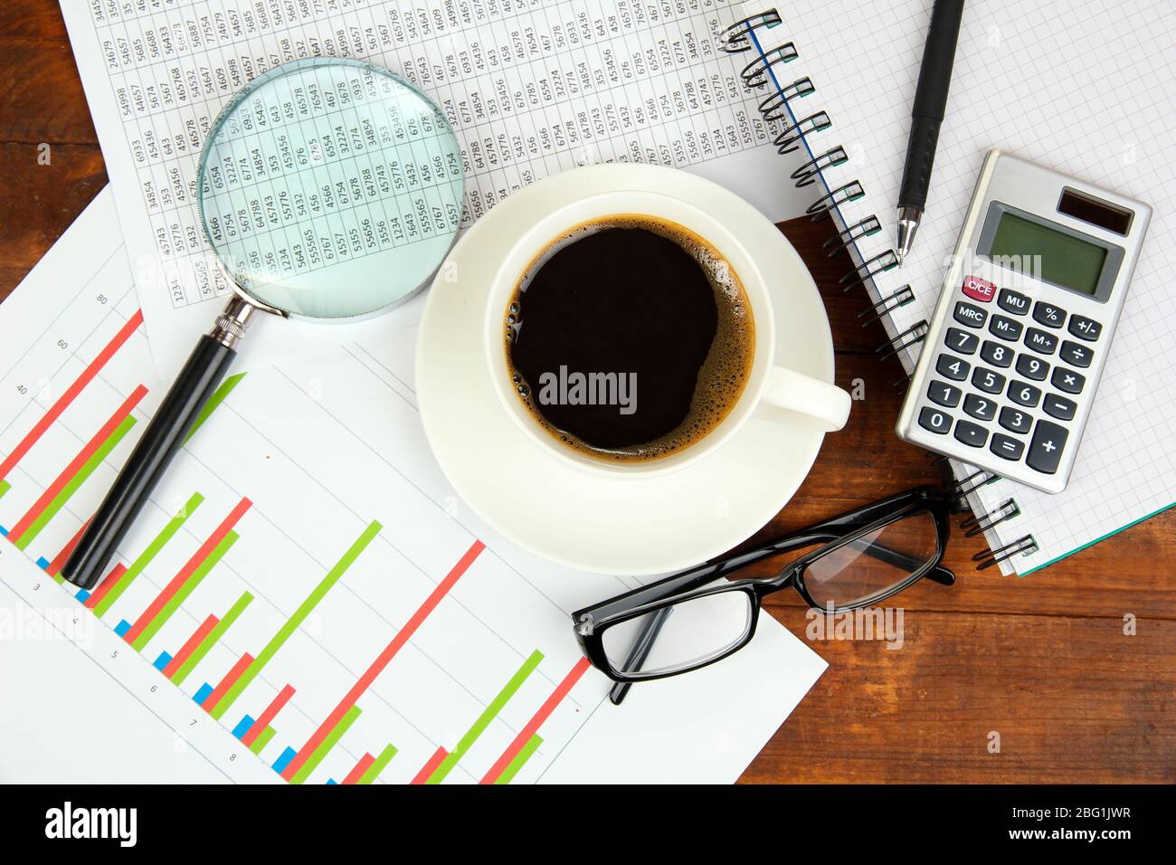 Cup of coffee on worktable covered with documents close up Stock Photo