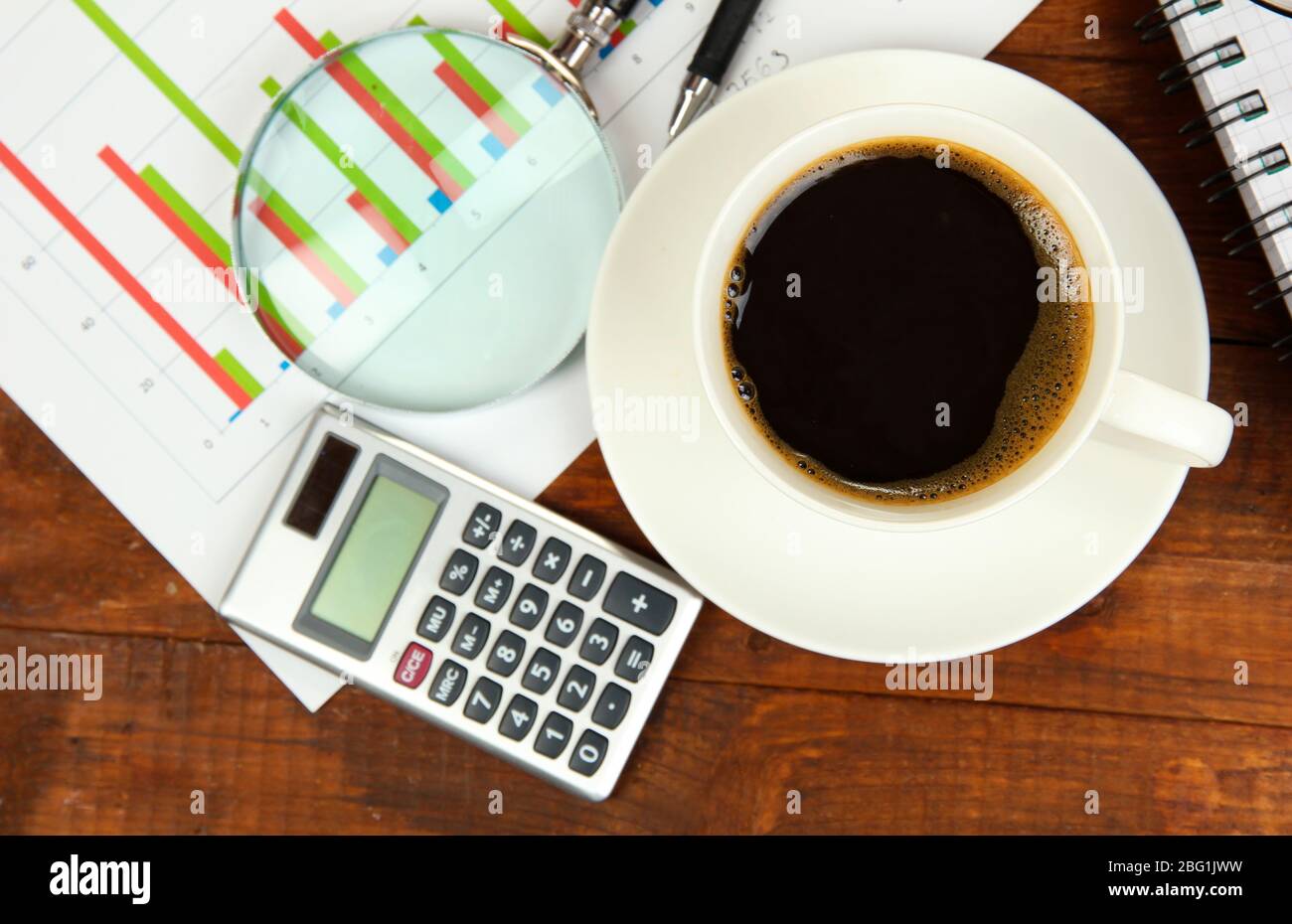 Cup of coffee on worktable covered with documents close up Stock Photo