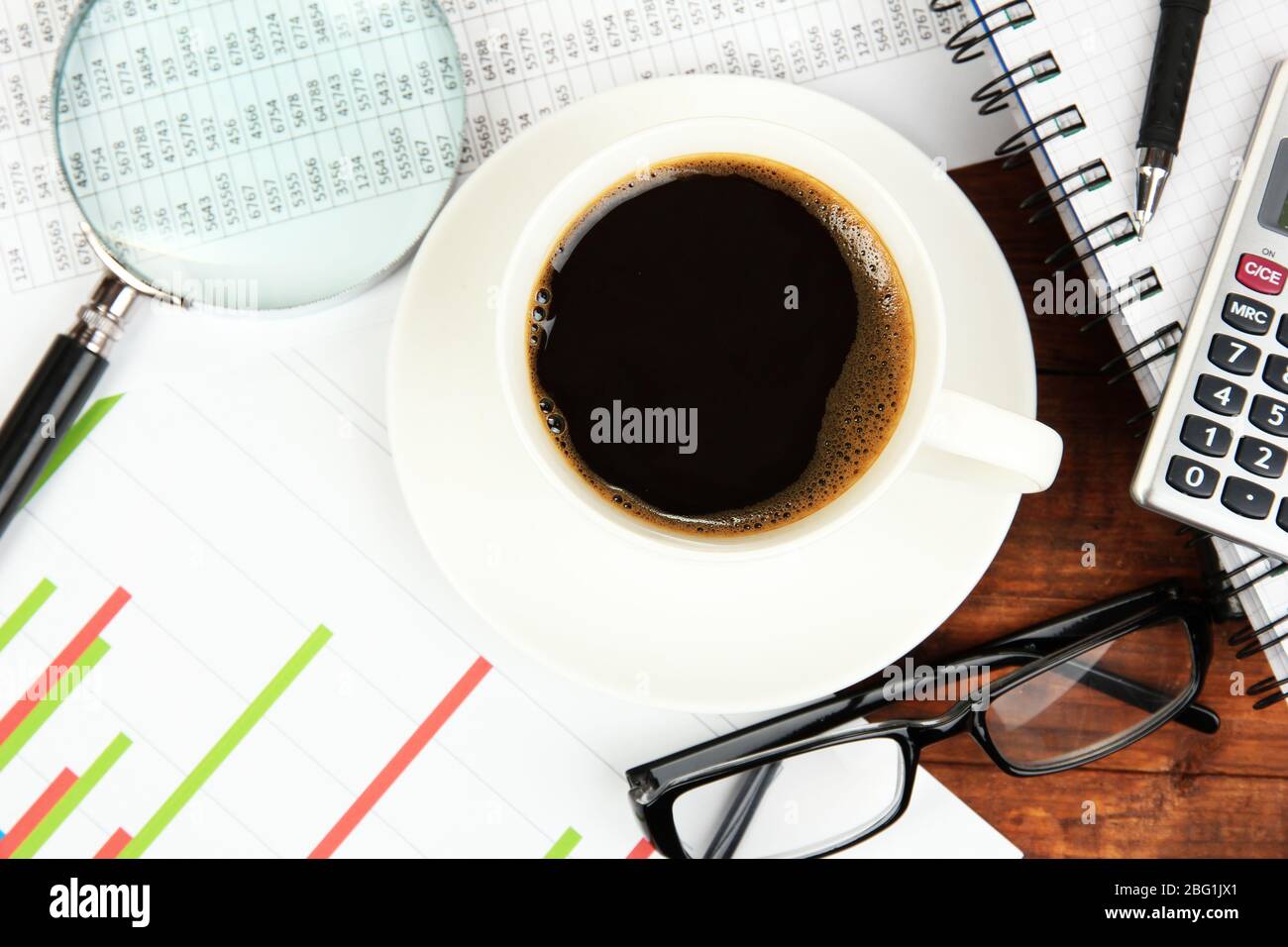 Cup of coffee on worktable covered with documents close up Stock Photo