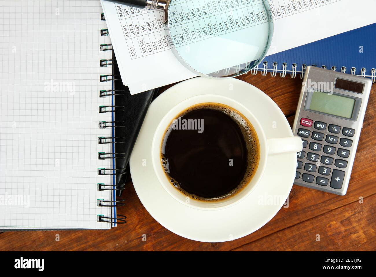 Cup of coffee on worktable covered with documents close up Stock Photo