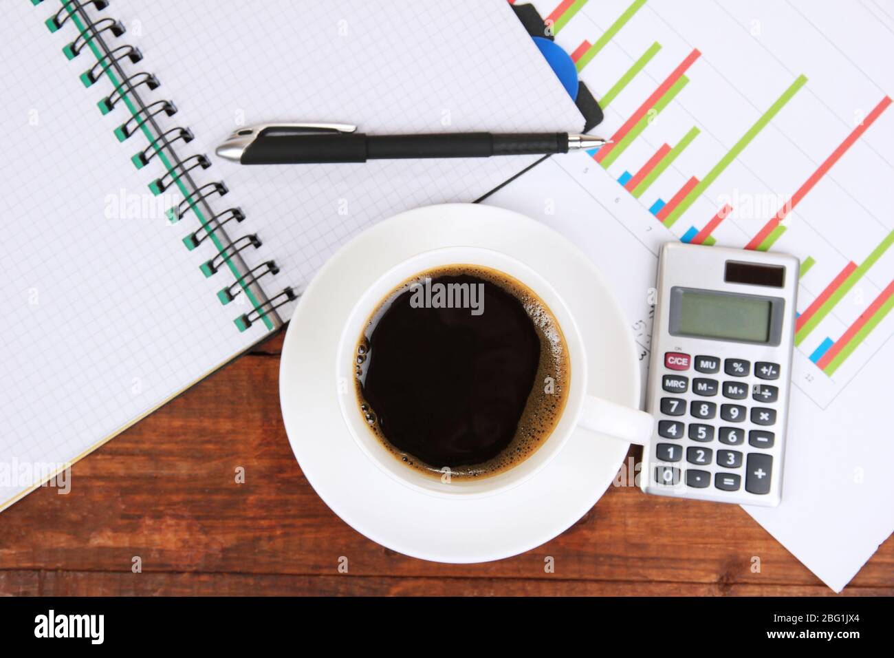 Cup of coffee on worktable covered with documents close up Stock Photo