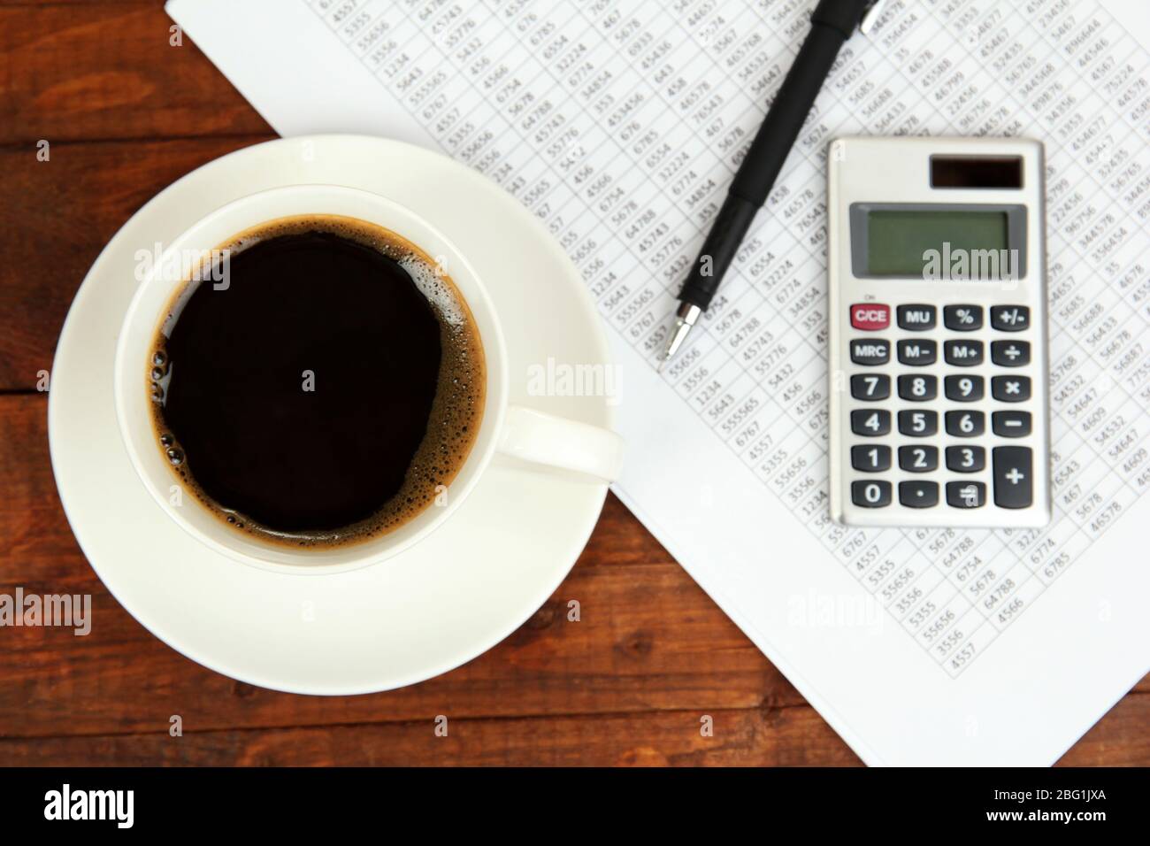 Cup of coffee on worktable covered with documents close up Stock Photo