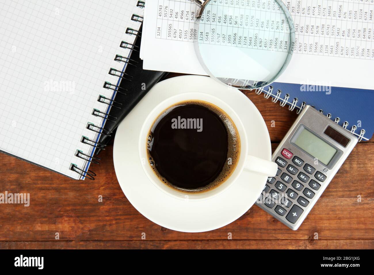 Cup of coffee on worktable covered with documents close up Stock Photo