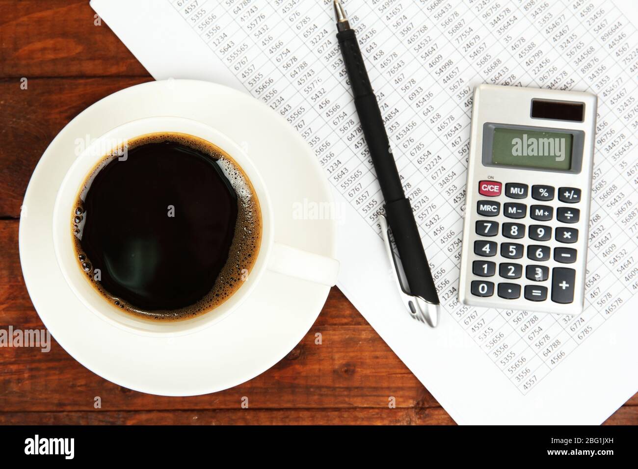 Cup of coffee on worktable covered with documents close up Stock Photo