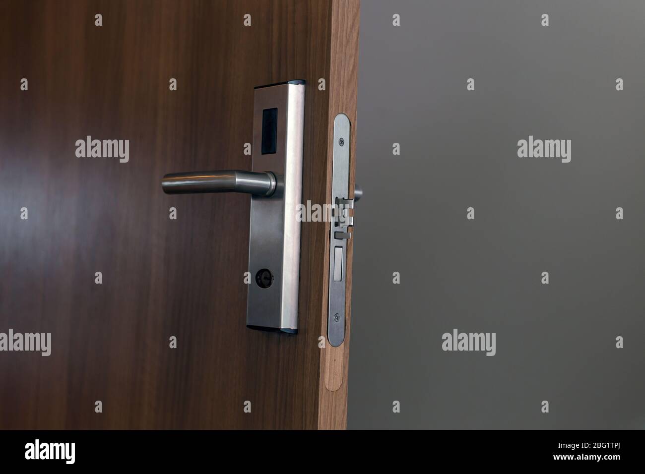 Wooden door with electronic lock. Close up view. Hotel key card door lock system. Stock Photo