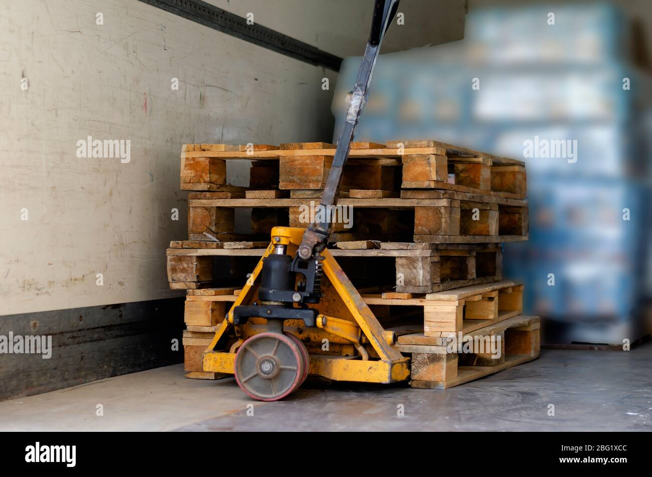 Hand pallet truck inside the truck. Empty wooden pallets and pallets