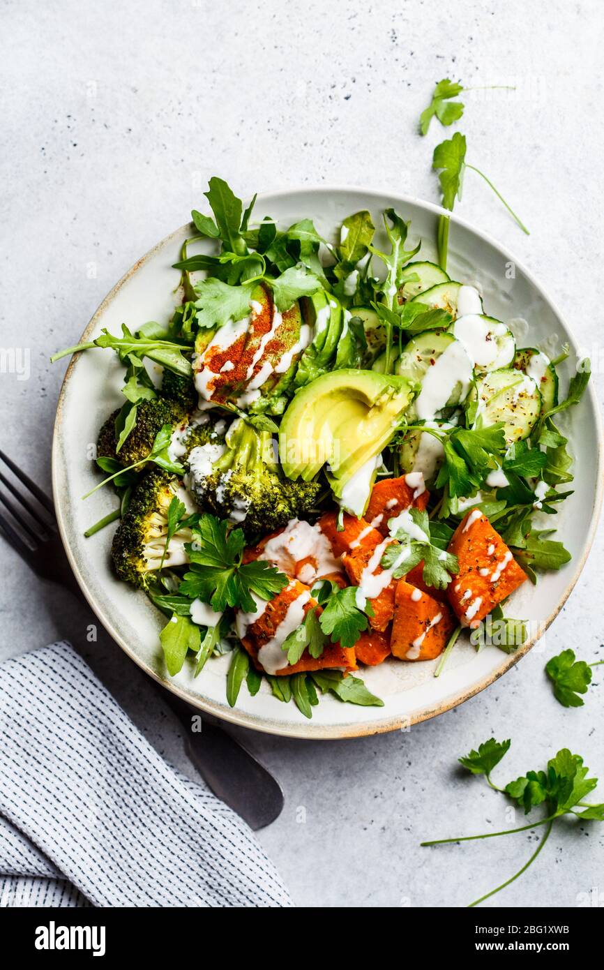 Baked sweet potato, broccoli and avocado salad bowl with tahini